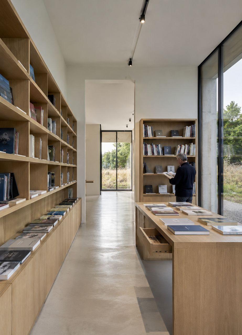 Librairie du centre avec tables de présentation, livres d’art et mobilier en bois clair.
